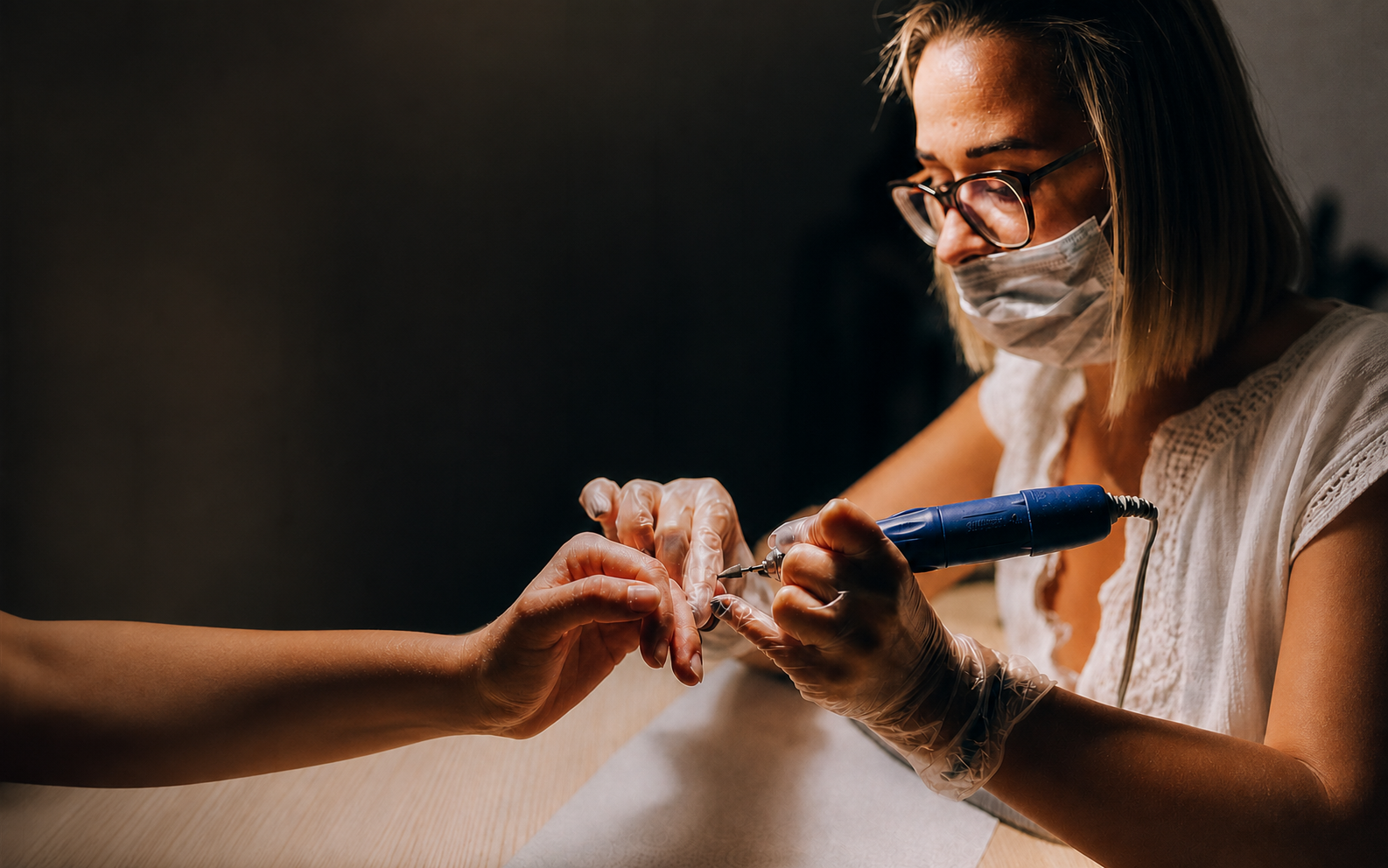 Manicurista trabajando las uñas de una clienta